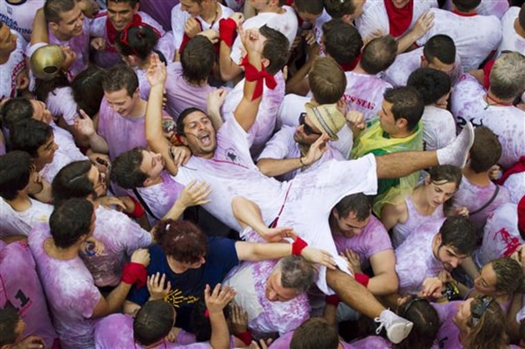 A man is held up by revelers, during the 'Chupinazo', the official opening of the 2011 San Fermin fiestas on Wednesday, July 6, 2011 in Pamplona, Spain. The festival of San Fermin, or the Pamplona bull running as it's more commonly known outside Spain officially begins at midday on 6th July every year with the 'chupinazo' which takes place on the balcony of the Casa Consistorial in Pamplona. Thousands of people congregate in the square awaiting the mayor's official announcement that the fiestas have begun, a rocket is launched and the partying gets underway.(AP Photo/Daniel Ochoa de Olza)
